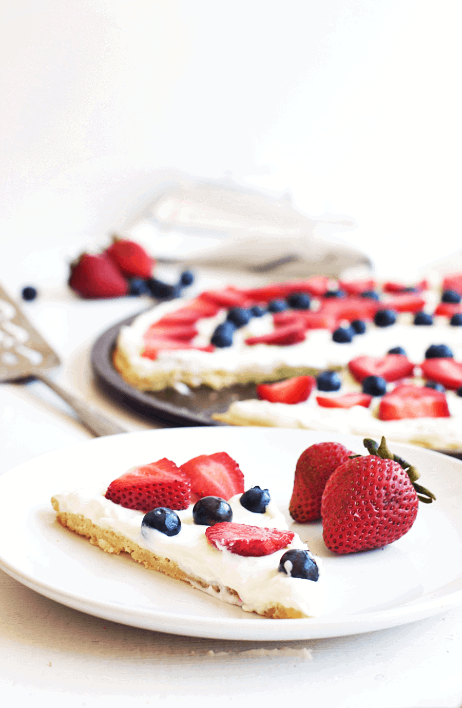 This 4th of July berry dessert pizza needs to be at the top of your list of festive foods to make! The combination of juicy, sweet berries and cream cheese icing spread on a sugar cookie crust is absolutely delicious. You’ll definitely be going back for seconds, maybe even thirds! || The Butter Half #easydessert #fruitpizza #summerrecipes #thebutterhalf