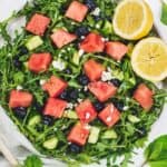 Overhead shot of plate of watermelon and arugula salad with lemons