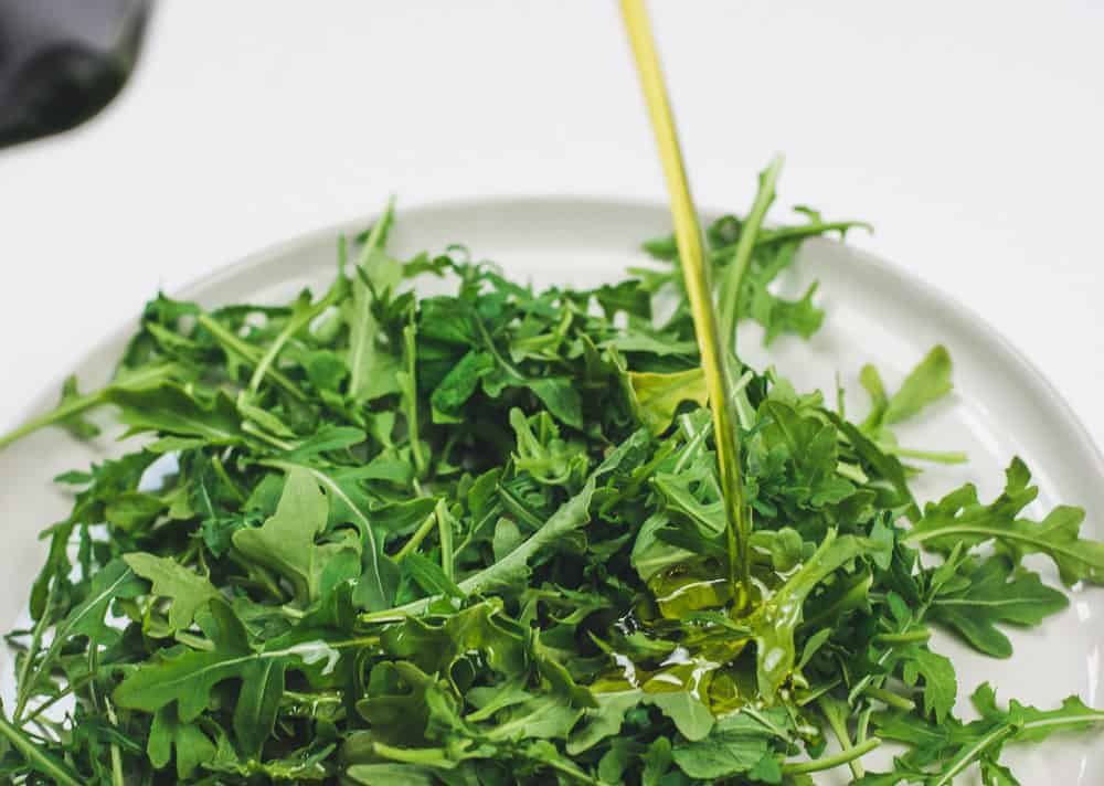 Pouring olive oil onto salad greens