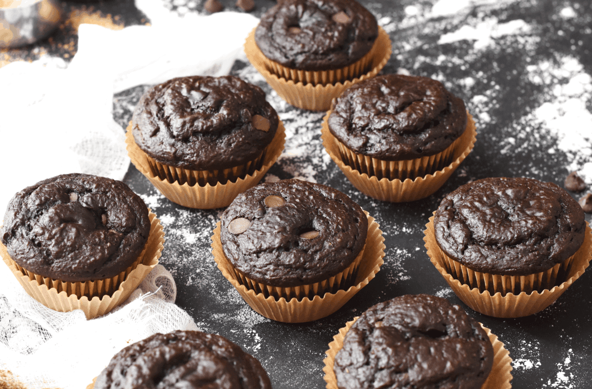 Up close shot of muffins on a black background with flour sprinkled.