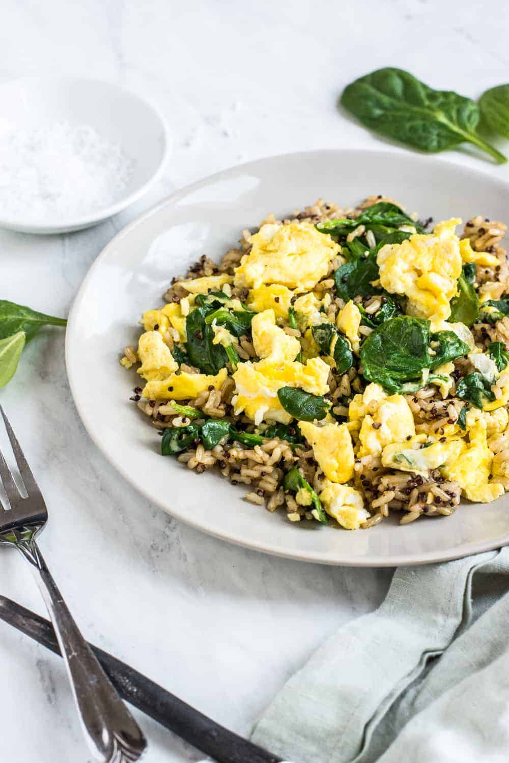 Up close shot of yellow scrambled eggs, brown rice, and cooked spinach
