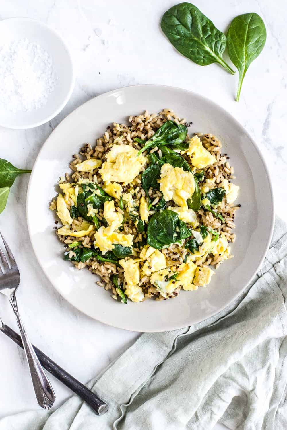 Overhead shot of brown rice and eggs with spinach on a gray plate