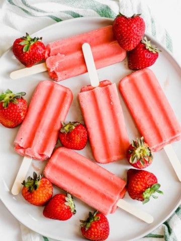 Overhead shot of strawberry popsicles on great plate with strawberries around it