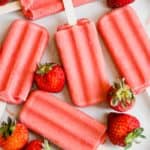 Overhead shot of strawberry popsicles on great plate with strawberries around it