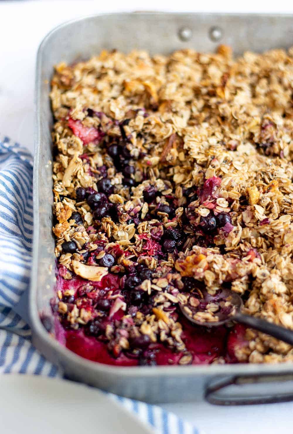angled shot of finished berry crisp in metal baking pan