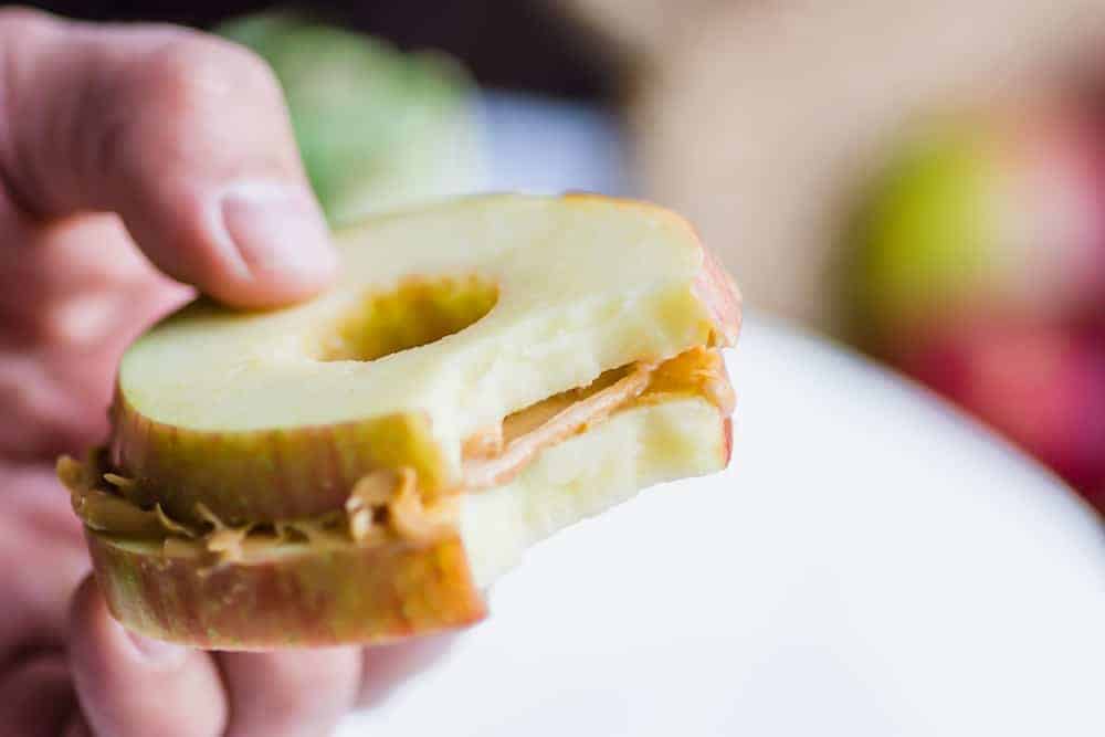 up close shot of apple and peanut butter sandwich with a bite in it
