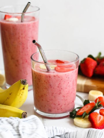 strawberry banana smoothie in a glass with a light colored background