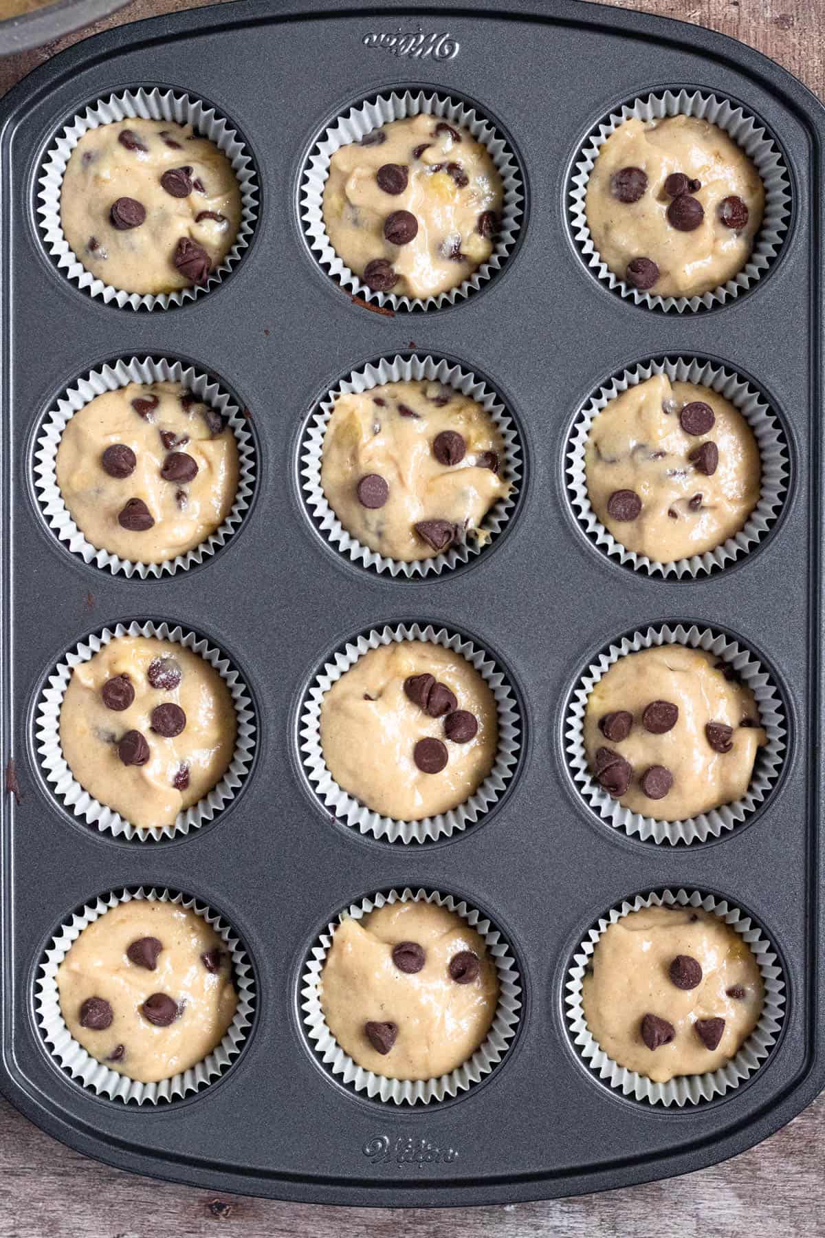 dark colored muffin tin filled with easy gluten free banana muffin batter