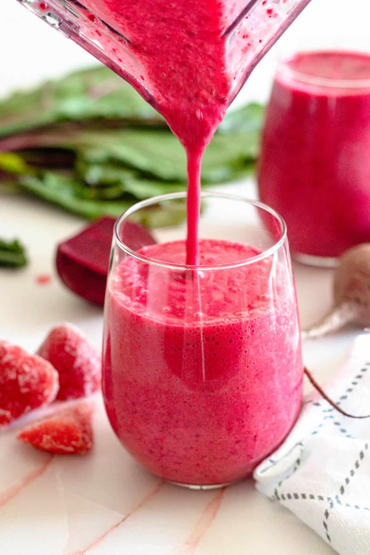 easy beet smoothie recipe being poured into a glass with a light colored background