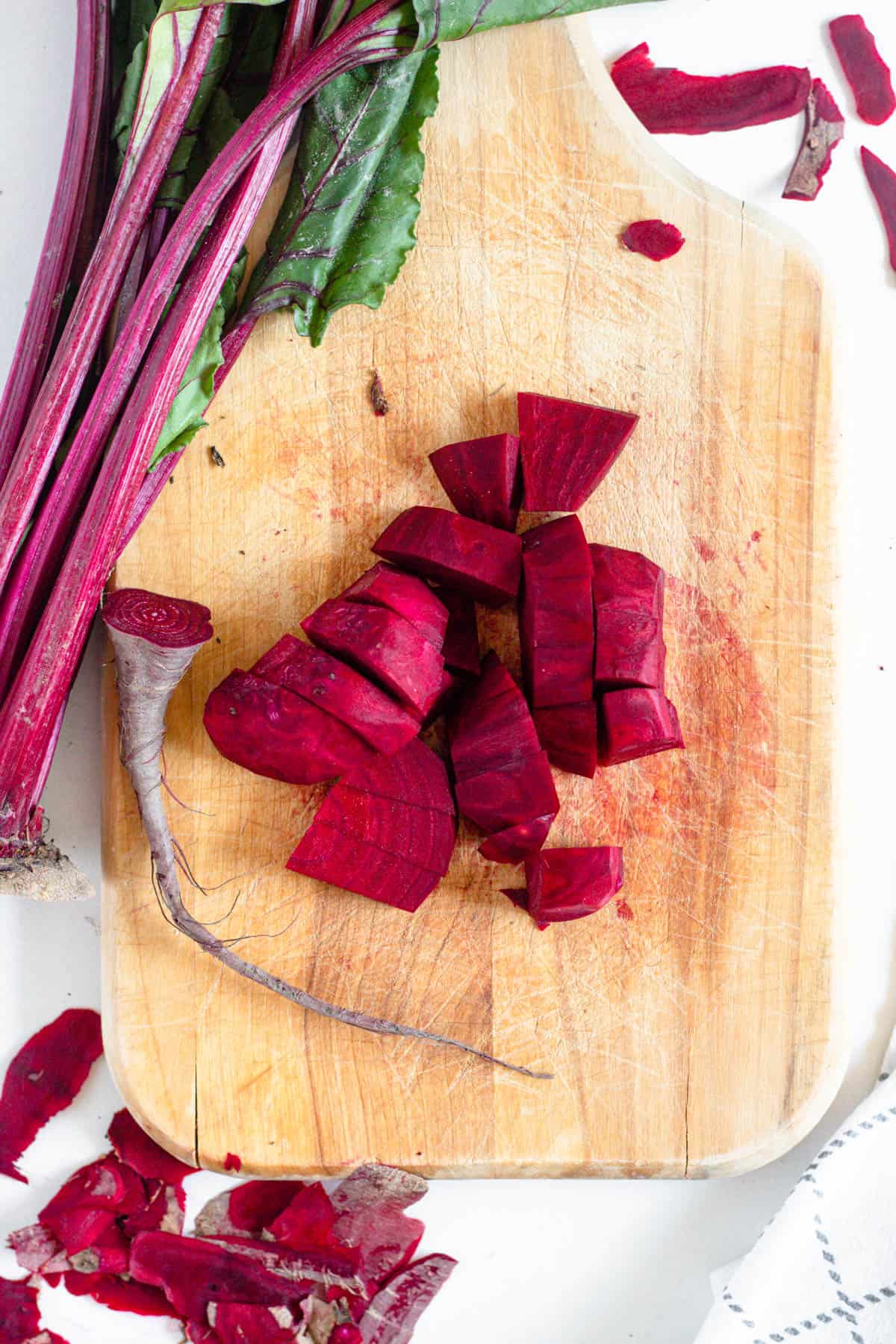 peeled beet on a wooden cutting board with a light colored background