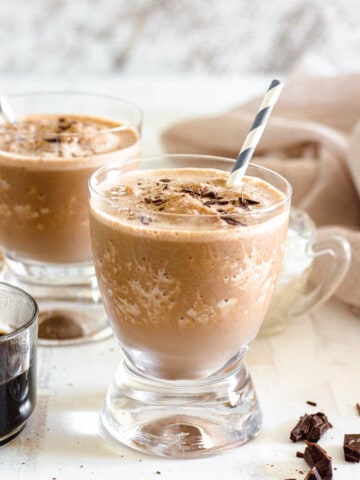 glass filled with coffee smoothie with a light colored background