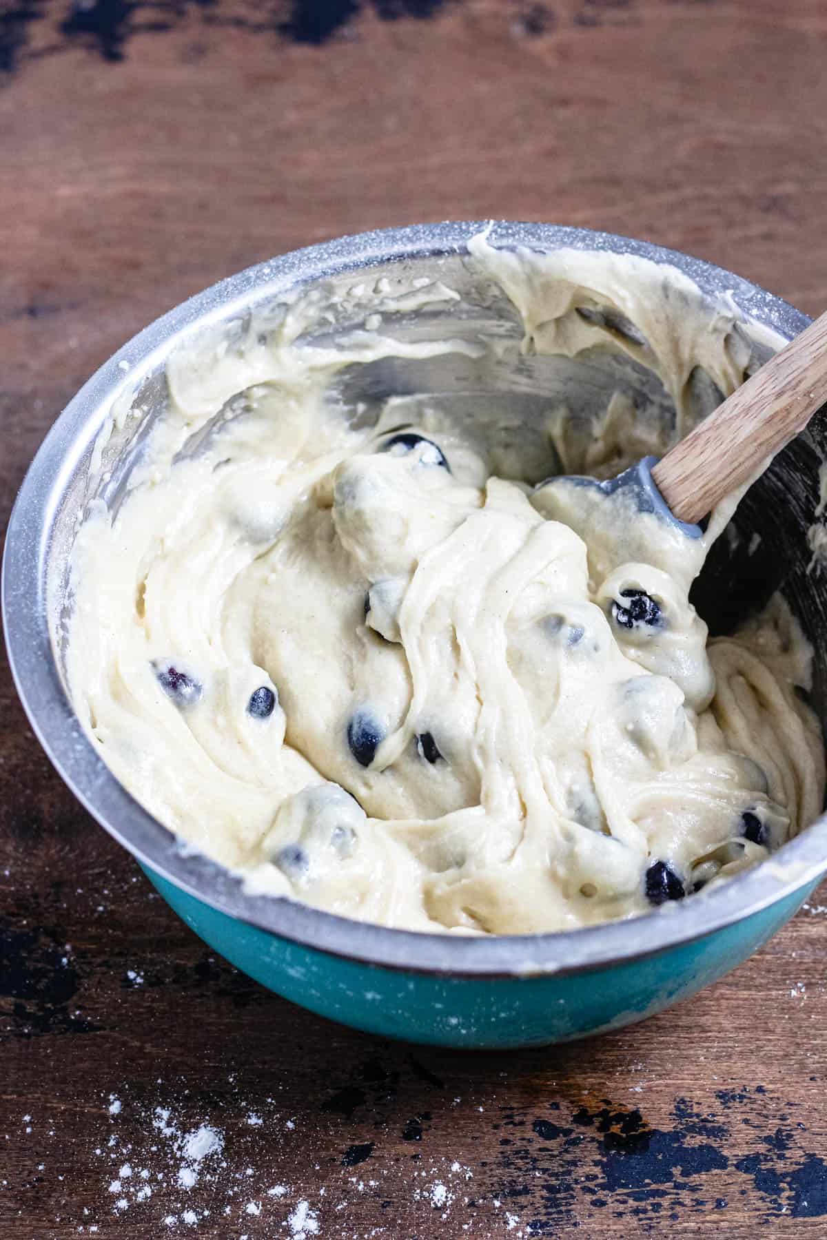 metal bowl with gluten free blueberry muffin batter with a dark colored background