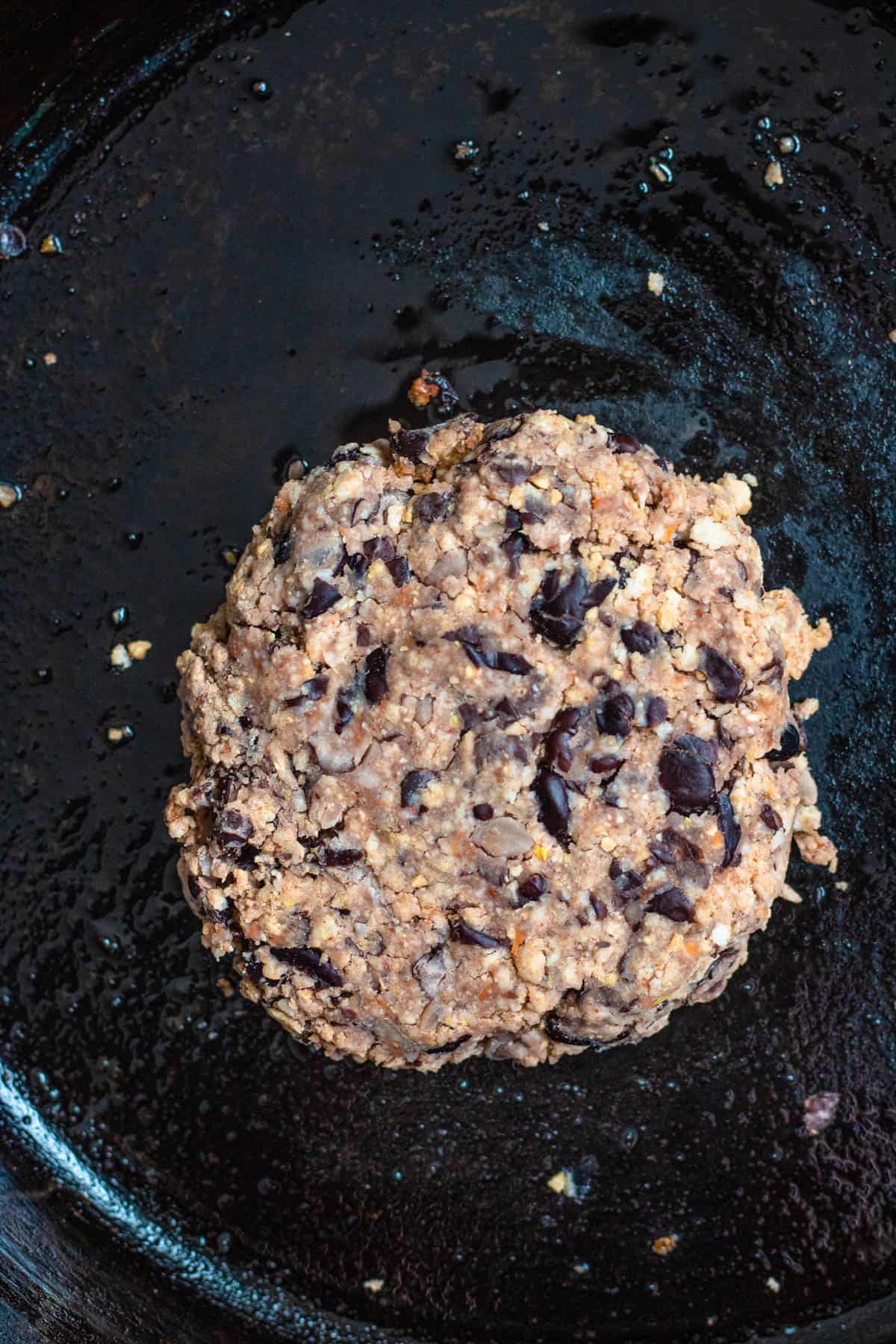 vegan black bean burger formed into a round on a pan ready to be cooked
