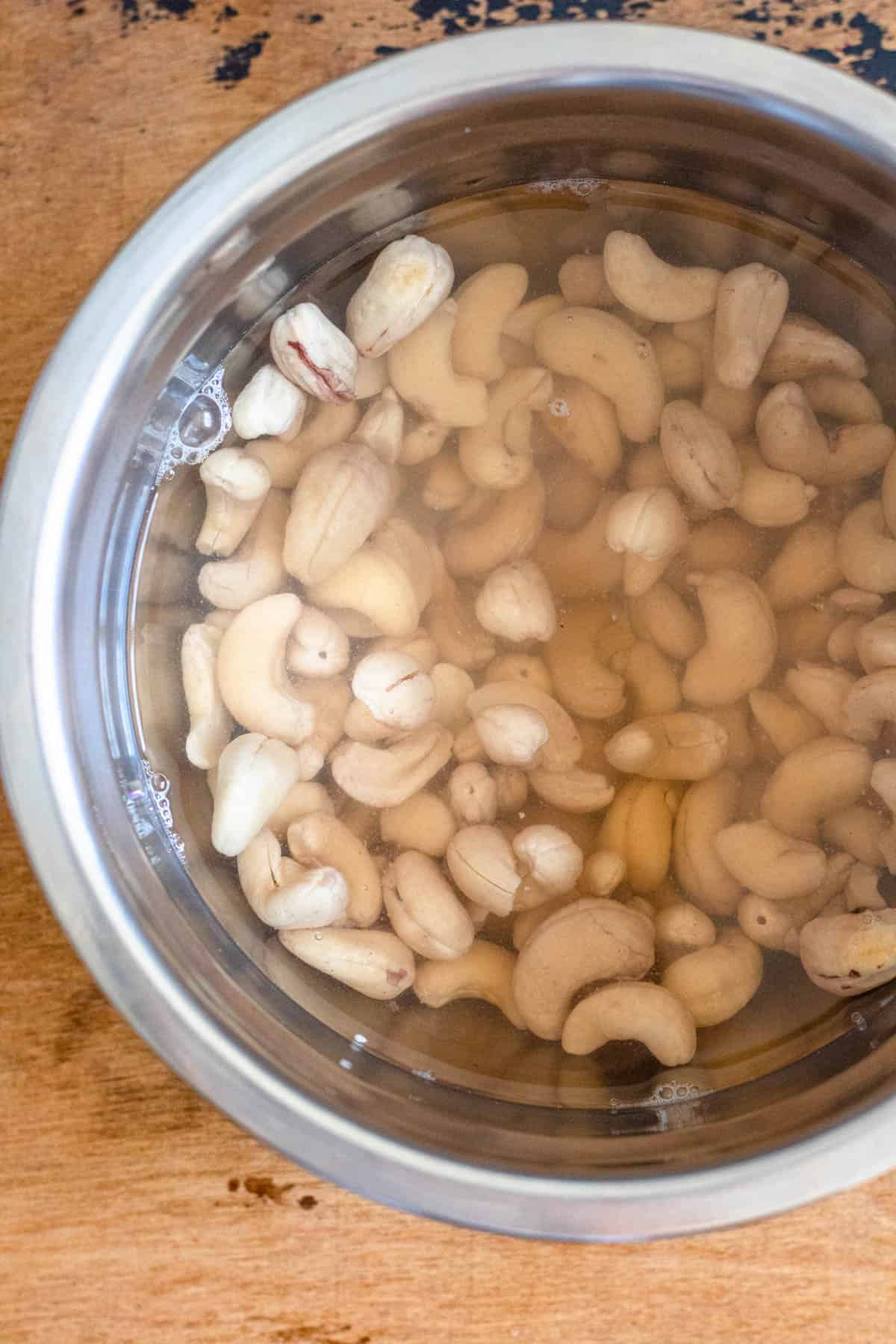 bowl filled with raw cashews covered in boiling water