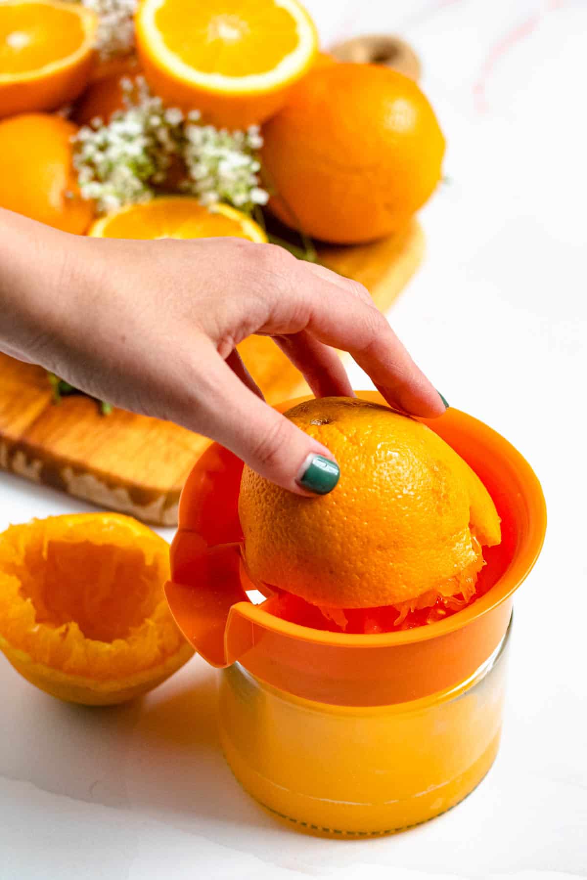 orange being juiced into a glass juicer with a white background