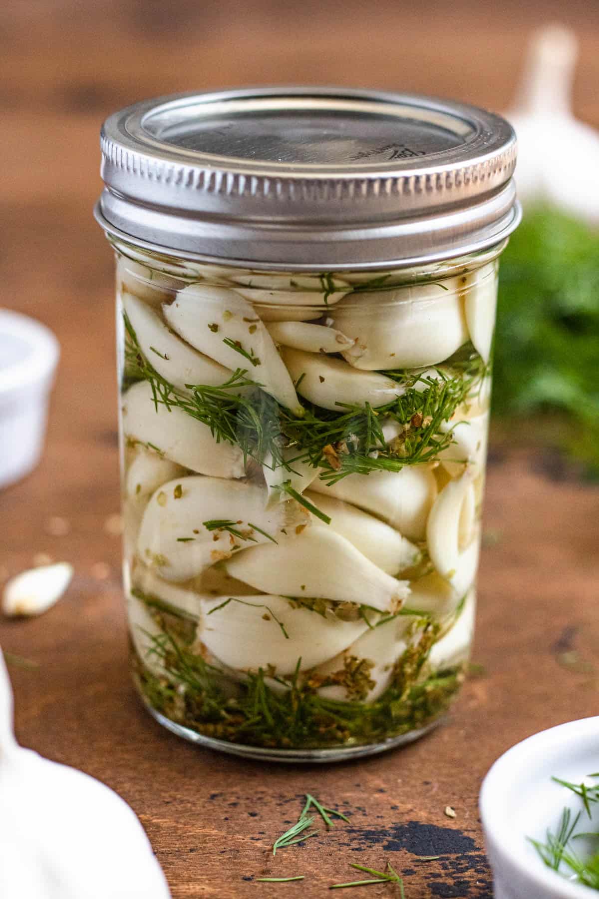 jar filled with pickled garlic topped with a silver lid with a dark colored background