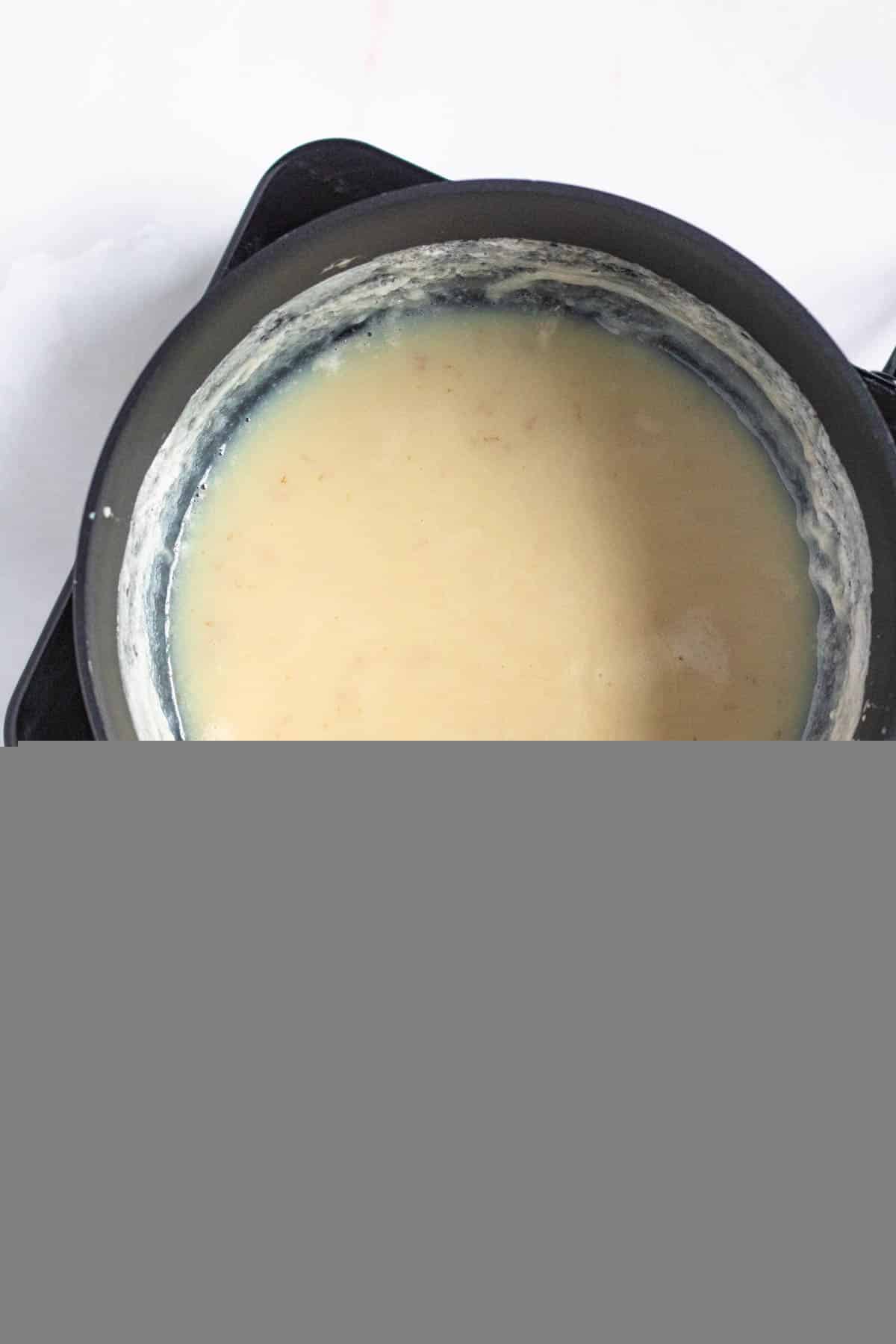 medium sized pot with whole milk and sugar combined and golden brown with a light colored background