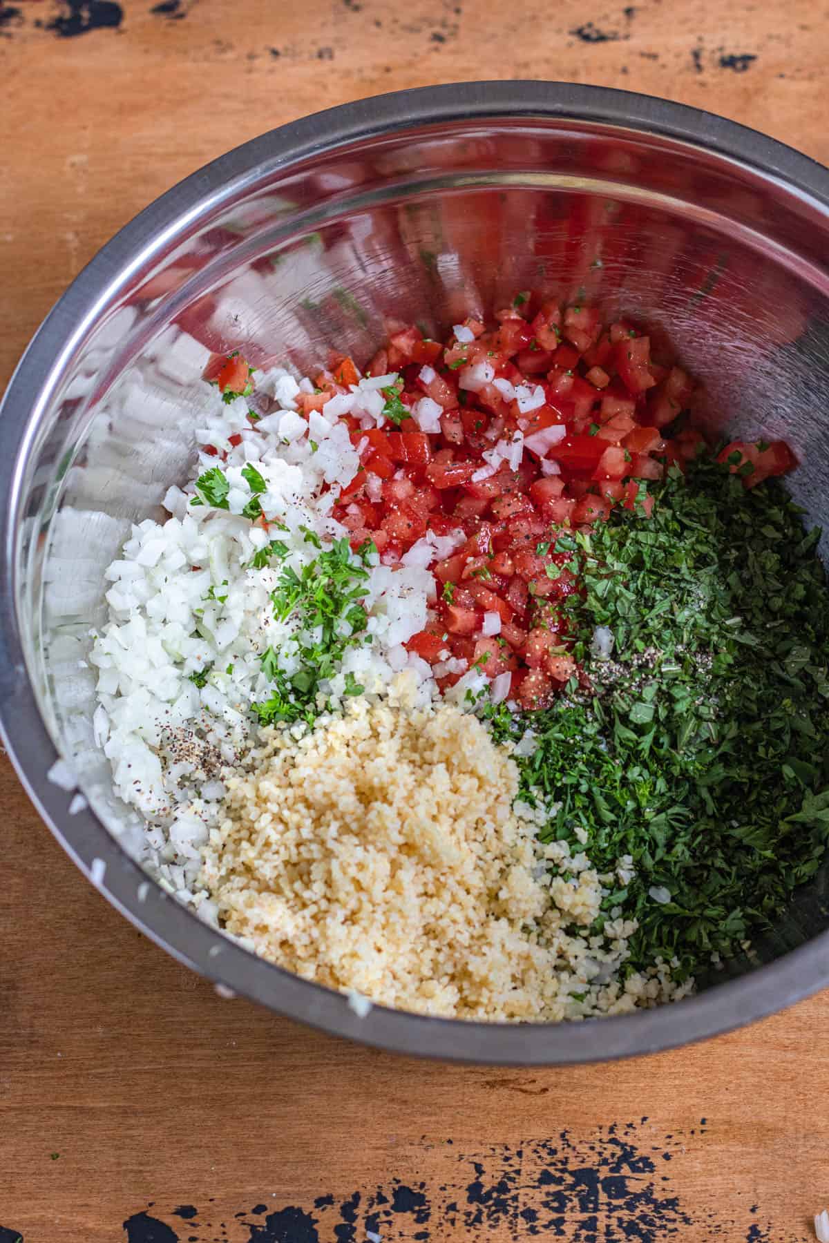 chopped parsley, tomatoes, mint, onion, and hydrated bulgur in a medium bowl
