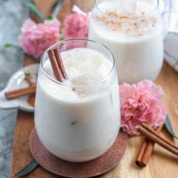authentic mexican horchata in small glasses with ice and cinnamon sticks with a light colored background