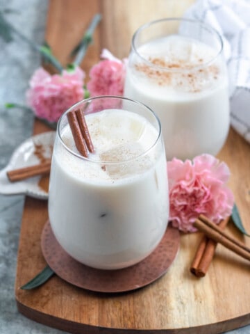 authentic mexican horchata in small glasses with ice and cinnamon sticks with a light colored background