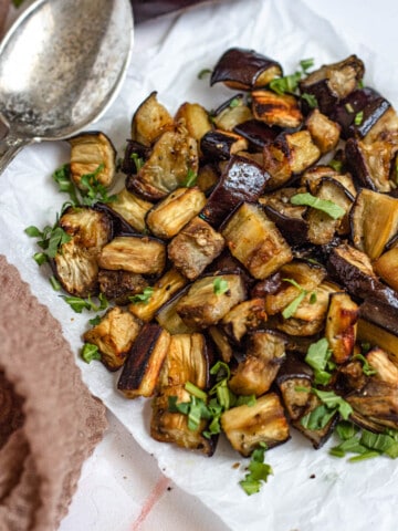 roasted eggplant diced and cooked in a serving bowl with a light colored background