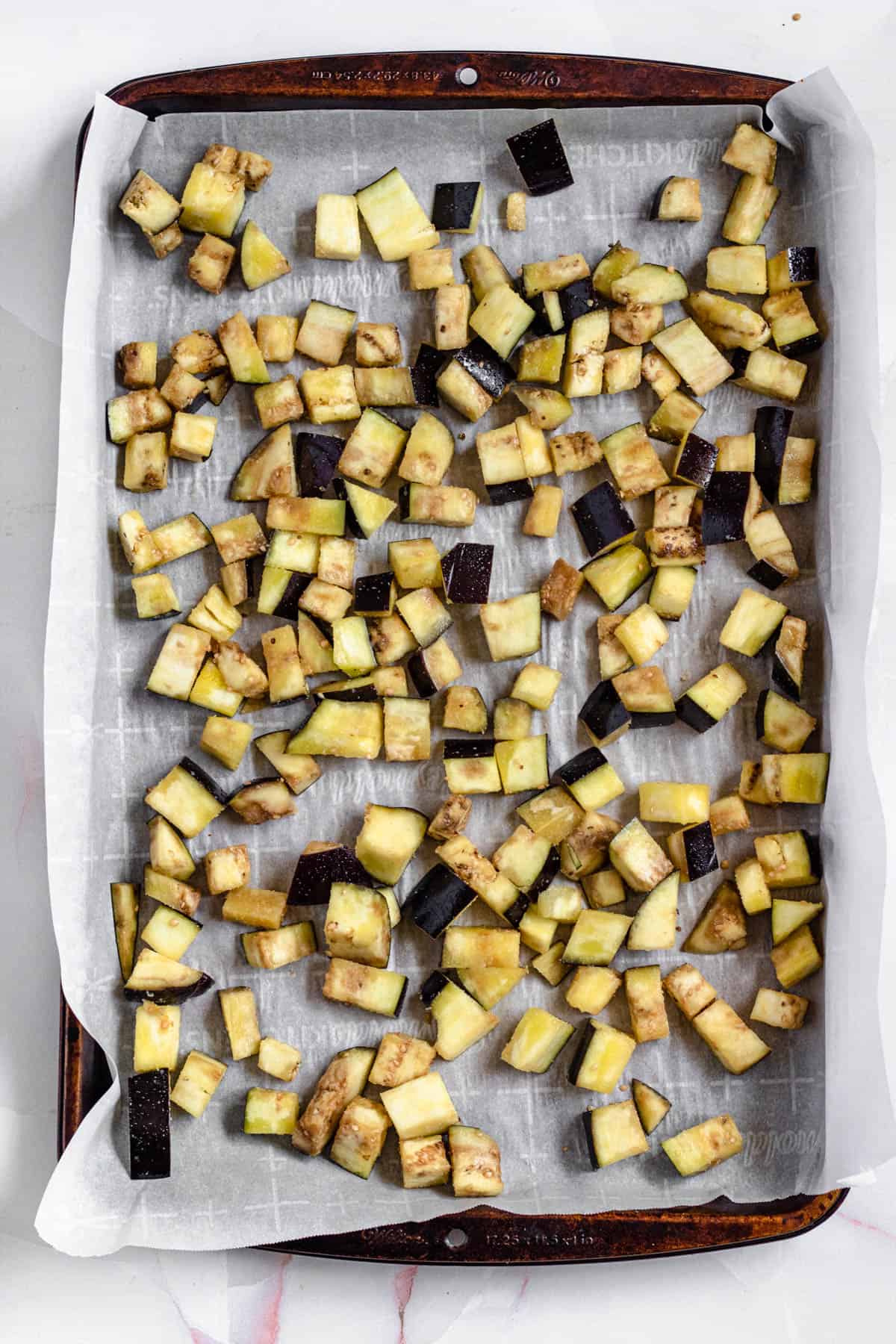 diced eggplant coated with olive oil, salt, onion and garlic powder on a baking sheet