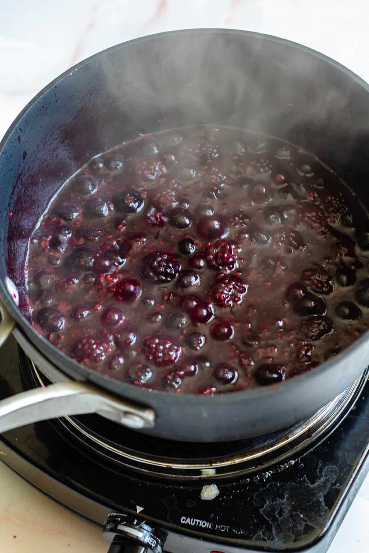 berries, lemon juice, and honey in a pot boiling
