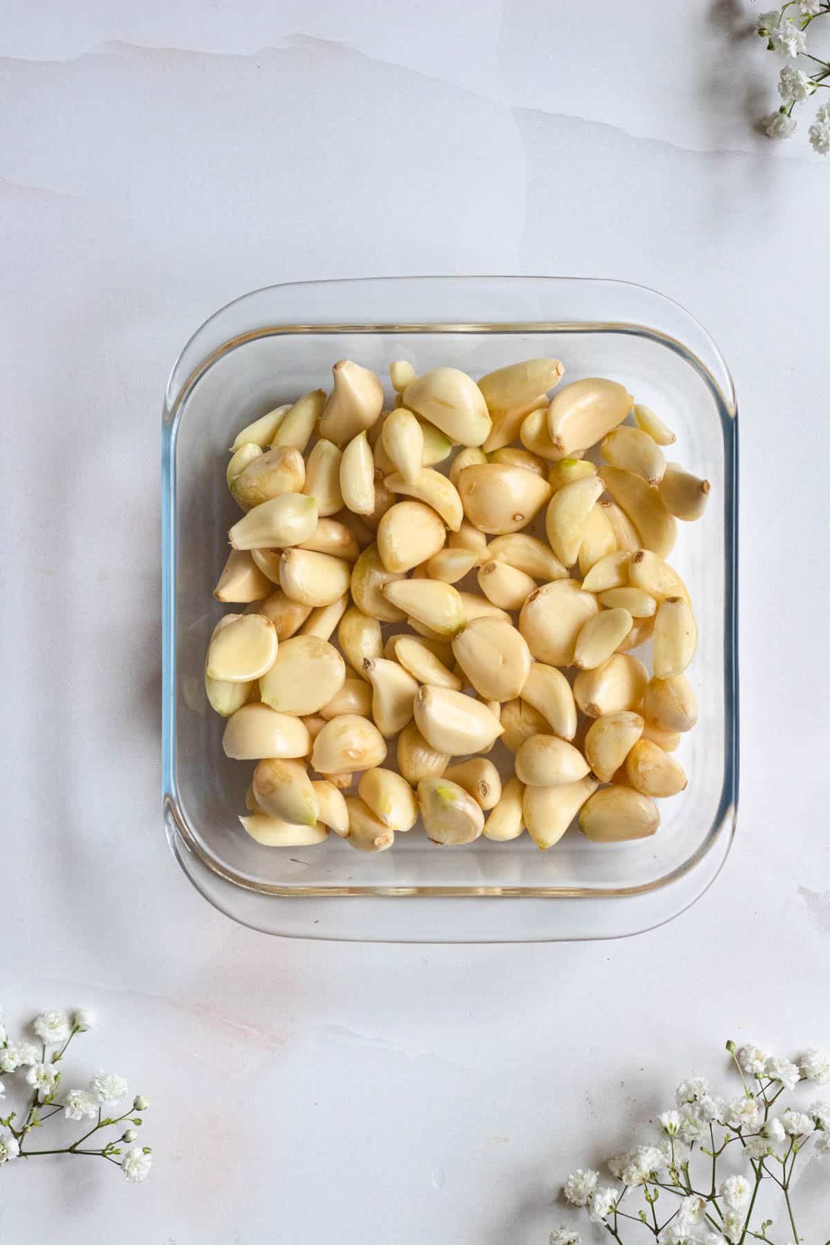 garlic cloves in oven safe pan with a light colored background