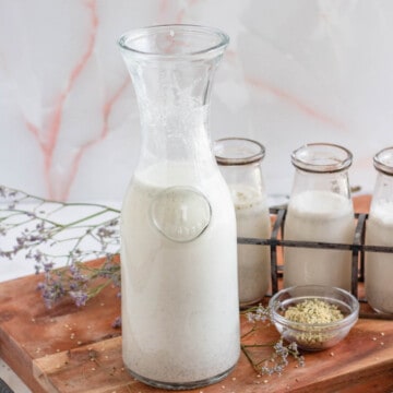 hemp milk recipe in a tall glass on a wooden cutting board with a light colored background