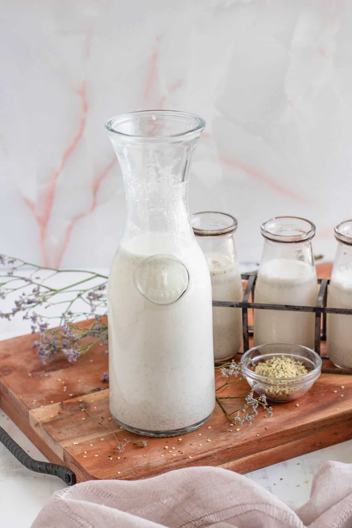 hemp milk recipe in a tall glass on a wooden cutting board with a light colored background