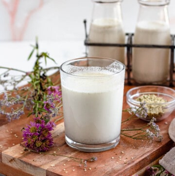 hemp milk in a glass on a wooden cutting board with a light colored background