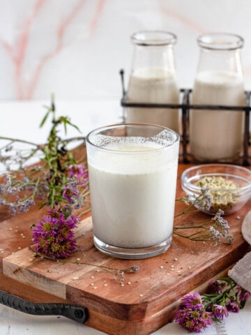 hemp milk in a glass on a wooden cutting board with a light colored background