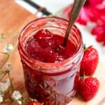 homemade strawberry jam in a small glass mason jar with a light colored background