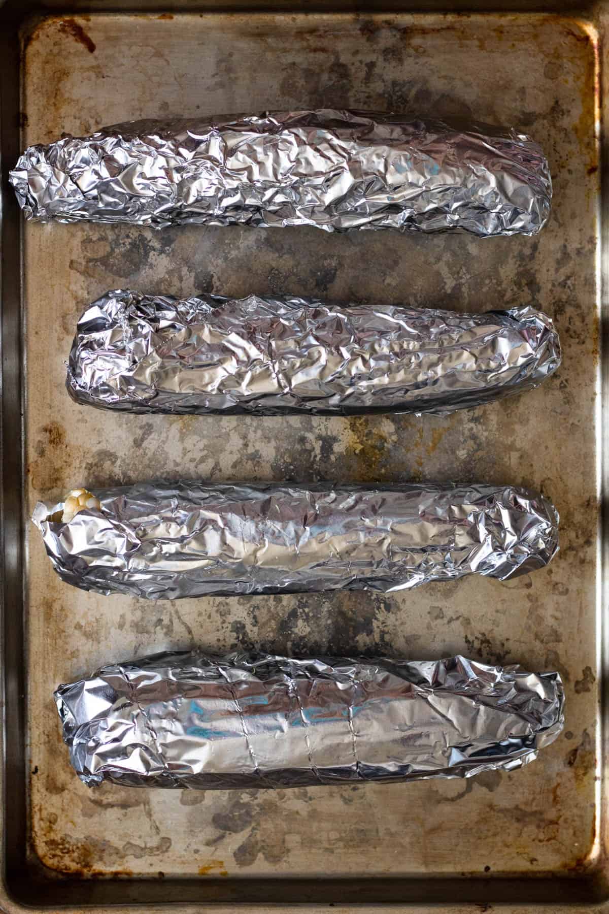 4 ears of corn wrapped in tin foil