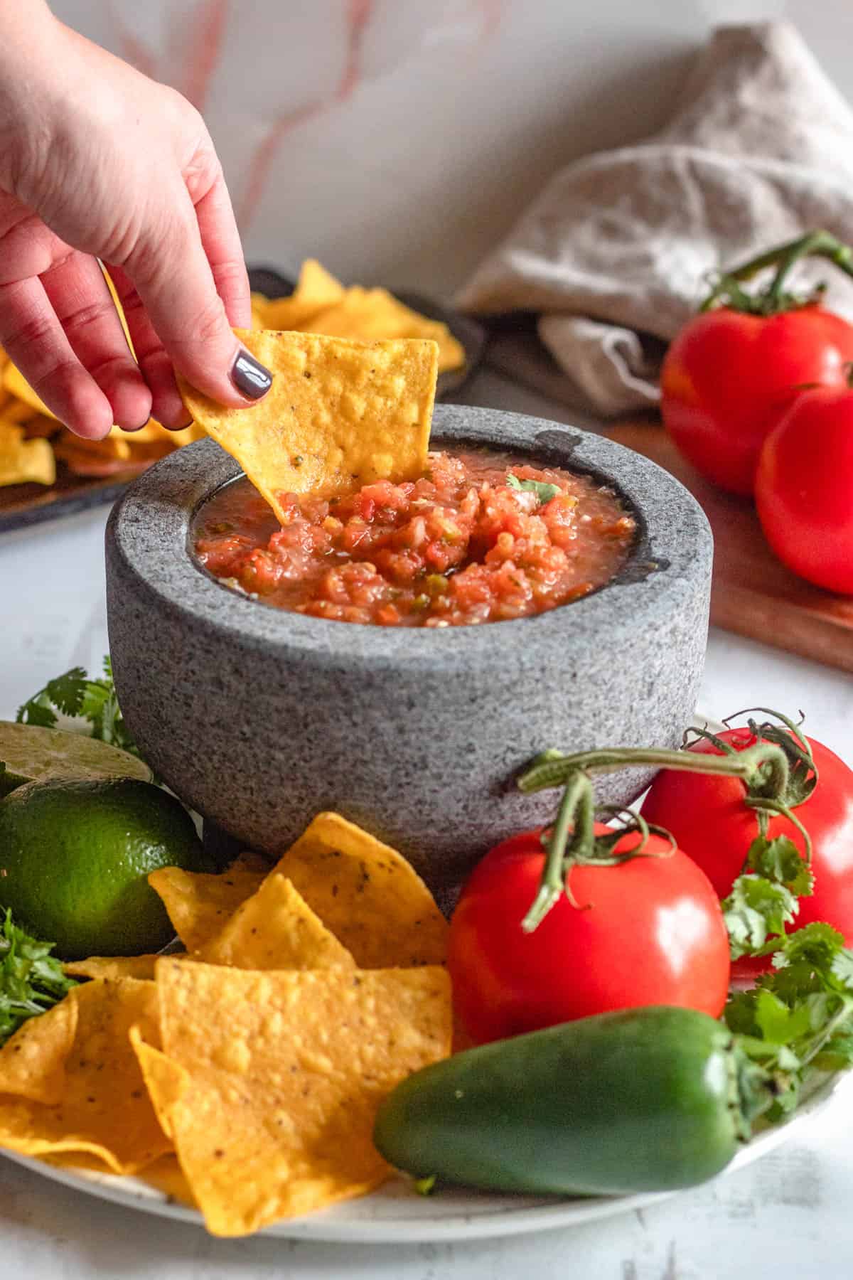 salsa roja in a small serving bowl with a tortilla chip being dipped into it 