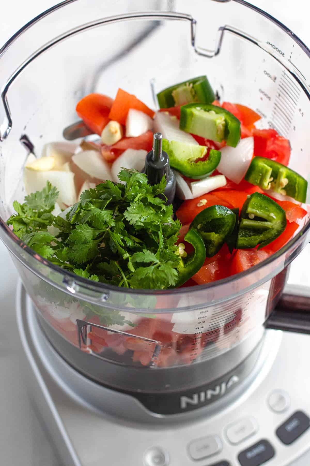 salsa roja ingredients in a food processor with a light colored background