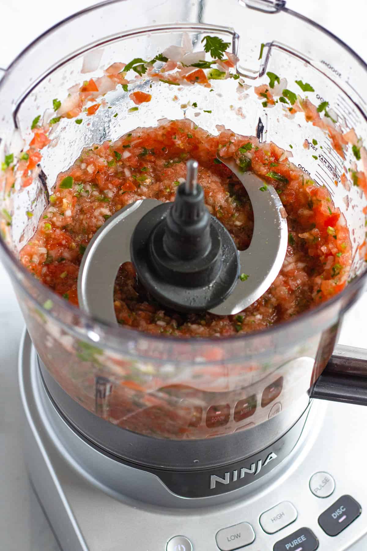 salsa roja ingredients blended in a food processor with a light colored background