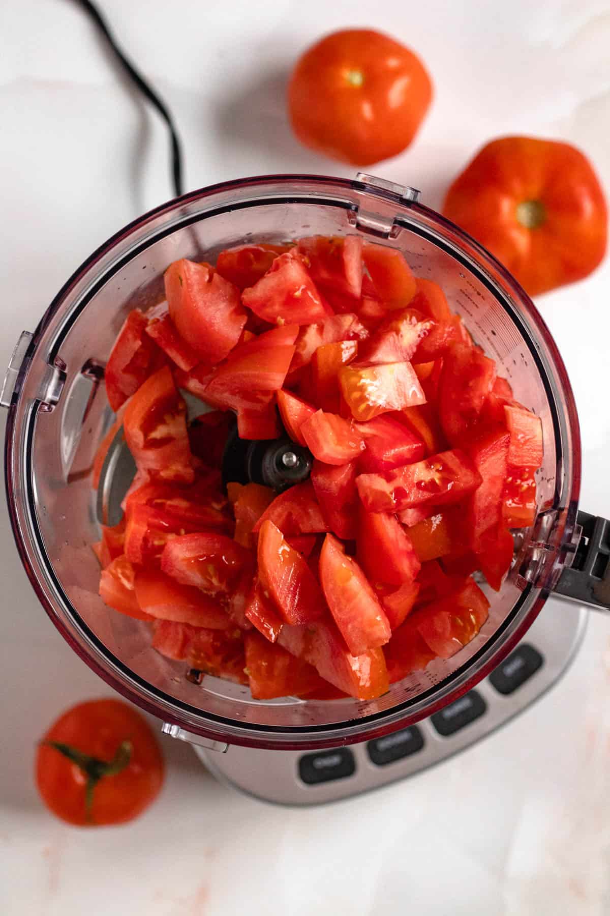 tomatoes in a food processor with a light colored background