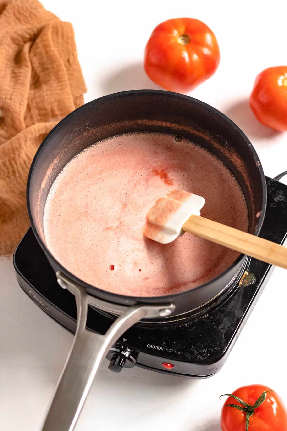 tomato juice warming in a pot with a light colored background