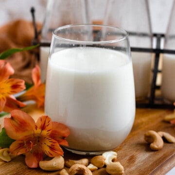 cashew milk in a small drinking glass with a light colored background