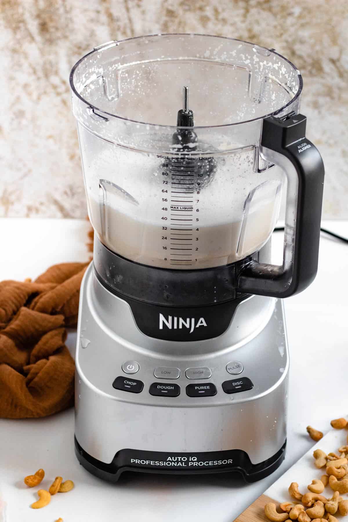 cashews, water, and maple syrup blended in food processor with a light colored background
