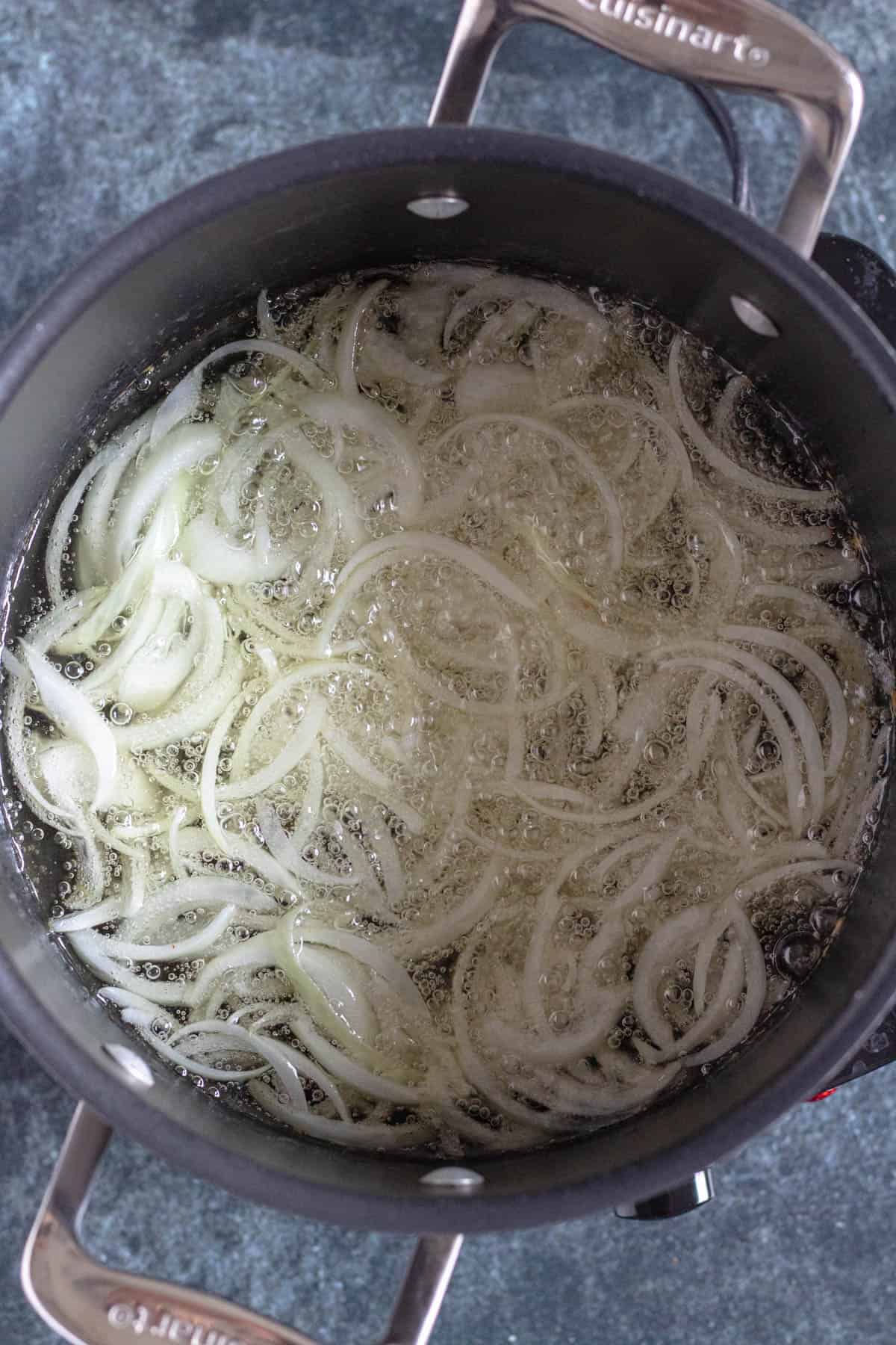 sliced onions in a large pot with oil