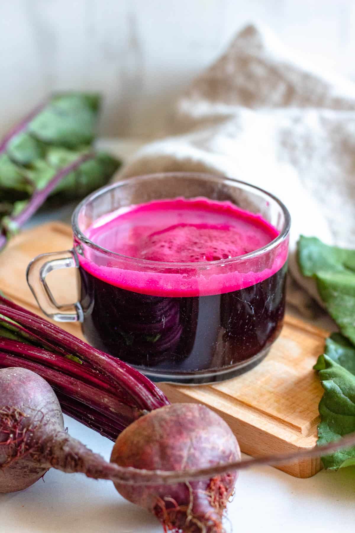 beetroot juice in a small glass with a light colored background