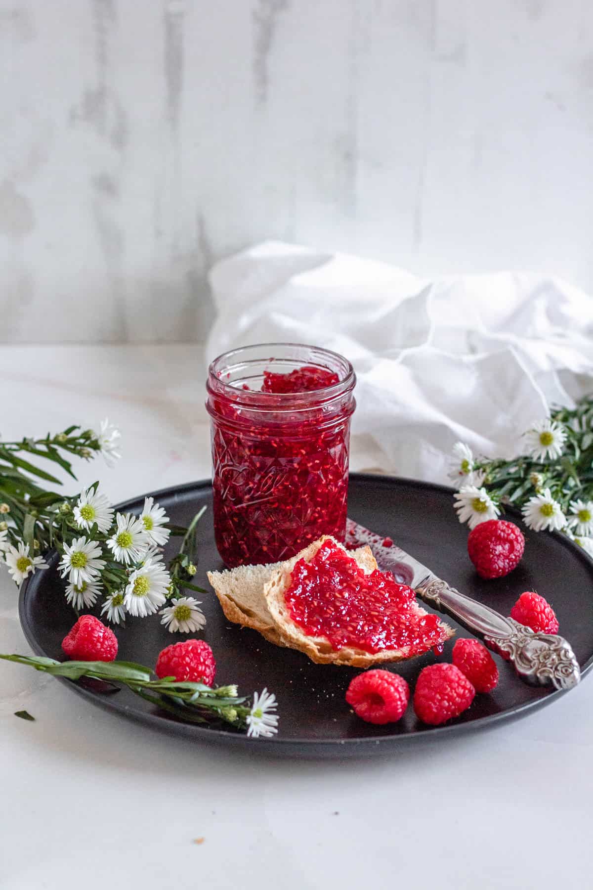 raspberry jam in glass jar with light background