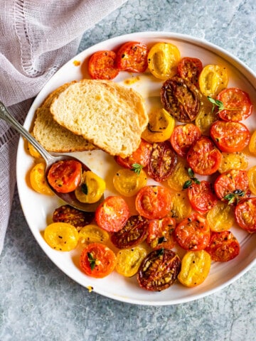 roasted cherry tomatoes on a round plate with a light colored background