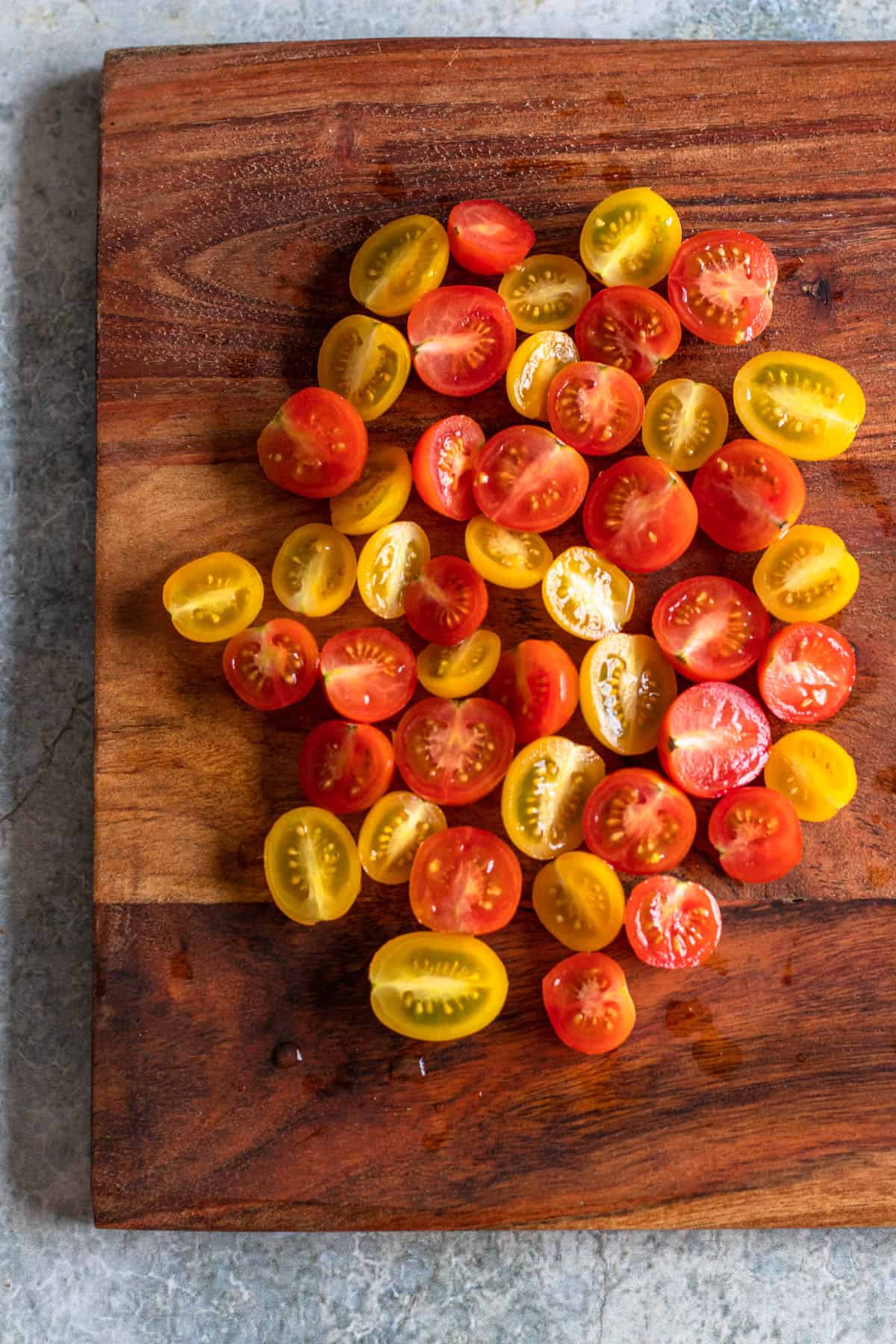 cherry tomatoes cut in half on a wooden cutting board